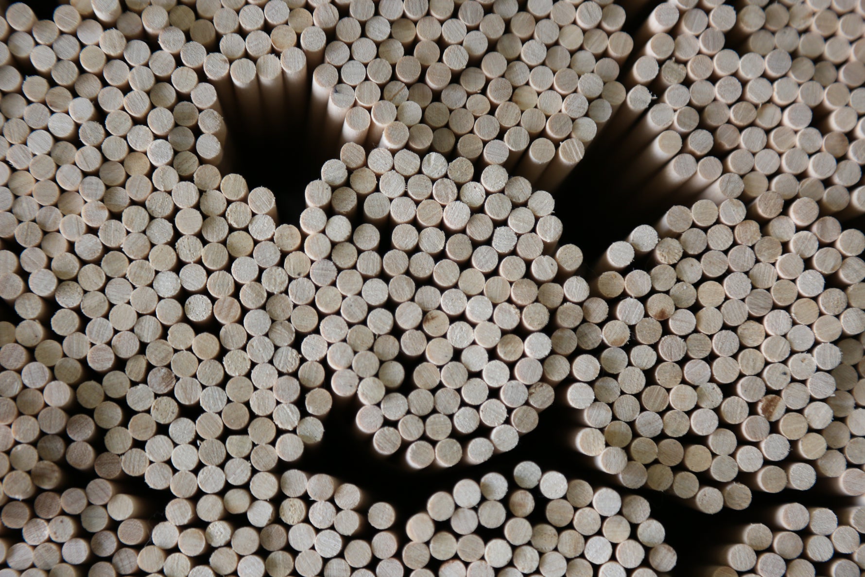 Bundles of wooden dowel rods stacked horizontally with cut ends visible