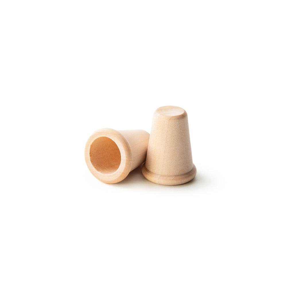 Two unfinished birch wood thimbles, one standing upright showing the tapered exterior and closed top, one lying on its side showing the interior hole